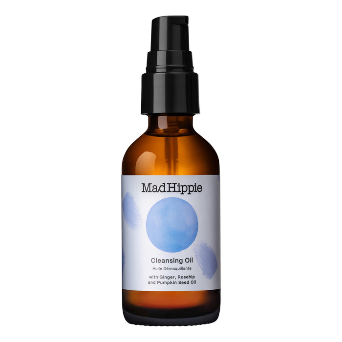 A brown glass bottle of Mad Hippie Cleansing Oil with a black pump dispenser and a white label featuring blue watercolor circles and product details in black text.