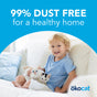 A smiling child in a light blue shirt sits on a white couch holding two kittens, with text above that says 99% dust free for a healthy home thanks to okocat Original Clumping Wood Cat Litter. The okocat logo is in the bottom right corner.
