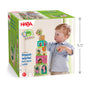 A toddler builds a tower with colorful farm-themed Stacking & Nesting Cubes - On the Farm on the product packaging.