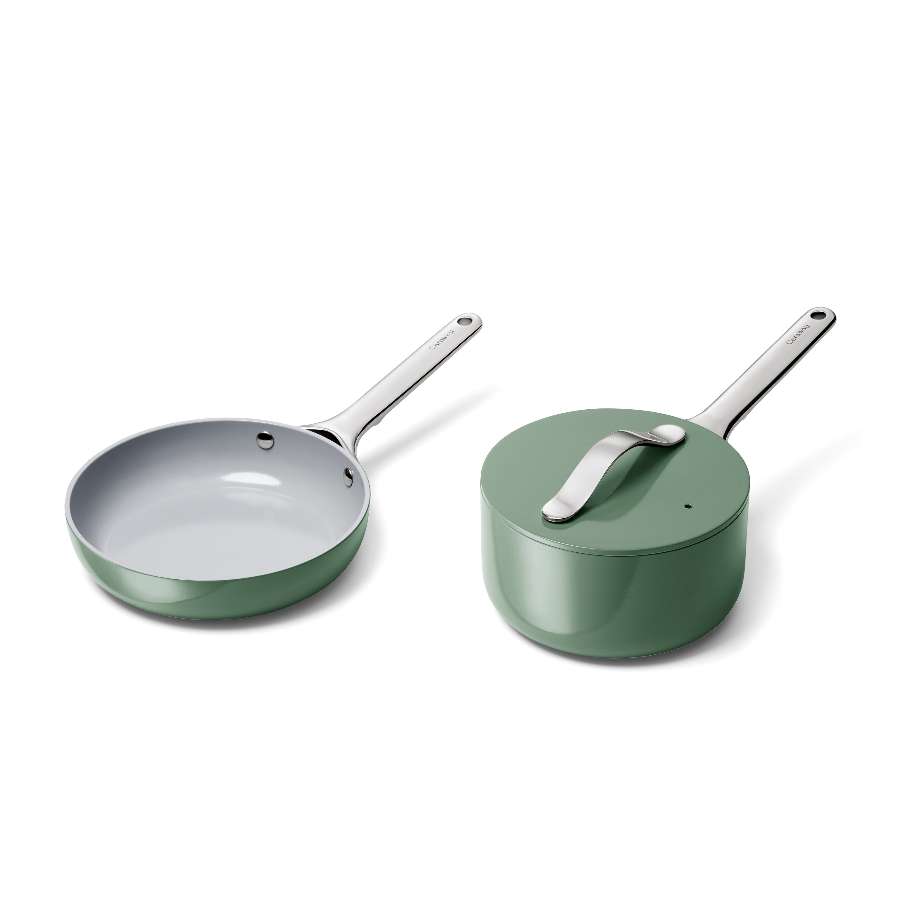 Caraways Ceramic Mini Fry Pan & Mini Sauce Pan Duo, with shiny metal handles and a pot lid featuring a curved handle, includes a green exterior with white interior. These items are designed for healthy cooking with non-toxic ceramic coating and are set against a white background.
