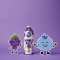 A bottle of Pacha Soap Co. bubble bath stands between two smiling cartoon fruit characters—a purple grape and a blue berry—against a solid purple background.