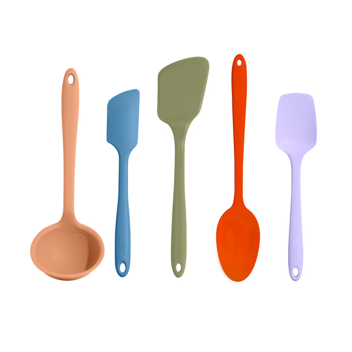 Five colorful silicone kitchen utensils—ladle, small spatula, slotted spatula, spoon, and wide spatula—are arranged upright in a row on a white background.