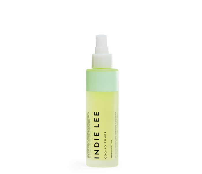 A clear plastic spray bottle labeled Indie Lee CoQ-10 Toner with a white spray cap and a light green liquid inside, standing upright on a white background.