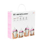 A white box labeled Comotomo Baby Bottle Bundle displays four baby bottles with pink lids held in hands. The box has a handle on top and pink sidebar text describing the contents and product features.
