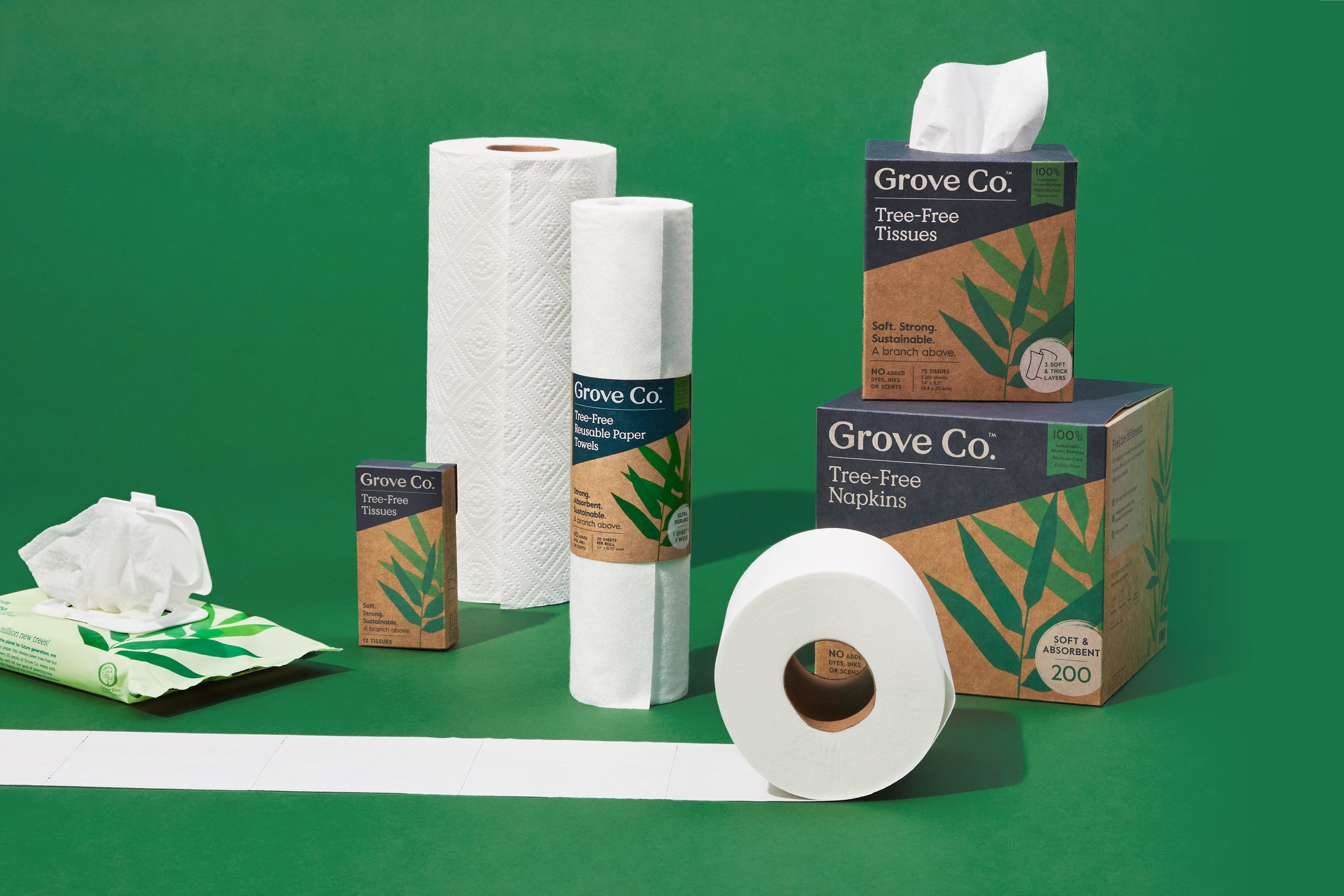 A variety of Grove Co. paper products, including tissues, napkins, paper towels, and toilet paper, are displayed on a green background. The packaging features green leaf designs.