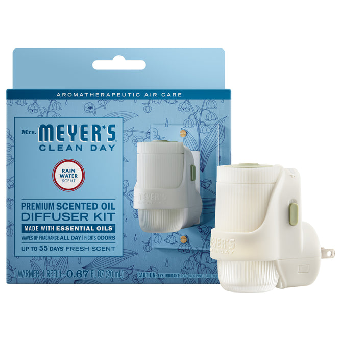A Mrs. Meyer's Premium Scented Oil Diffuser Kit in Rain Water scent, featuring the device and packaging in blue and white, provides garden-inspired fragrance with high-quality scented oils.