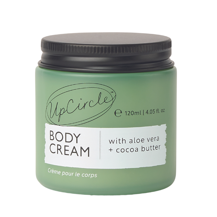 A green jar of UpCircle Body Cream with a black lid, labeled as containing aloe vera and cocoa butter. The jar holds 120 ml (4.05 fl. oz) and is labeled in both English and French.