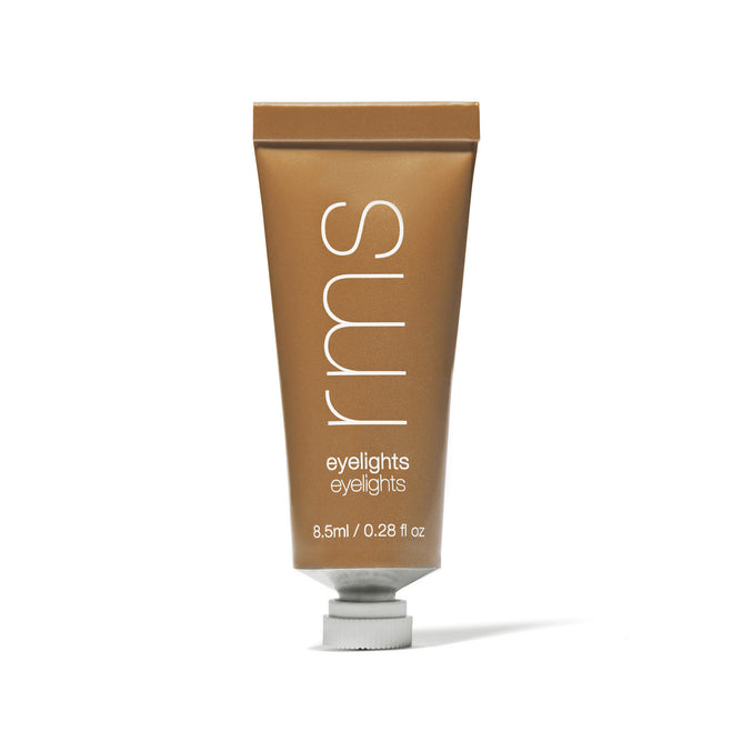 A metallic gold tube labeled rms eyelights containing 8.5 ml (0.28 fl oz) cream eyeshadow, standing upright with a white cap at the bottom.