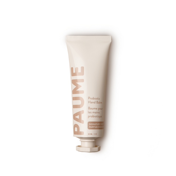 On a white background, a beige tube of PAUME Probiotic Hand Balm is displayed, enriched with natural probiotics and essential oils. The brand name appears in bold letters, with product details in smaller text.