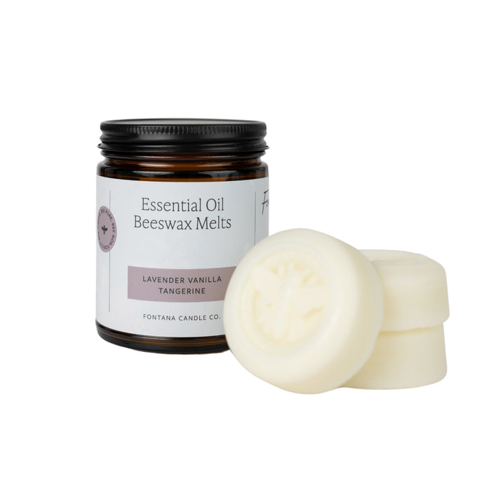 A brown glass jar labeled Essential Oil Beeswax Melts, Lavender Vanilla Tangerine stands next to three creamy white round wax melts, one showing a bee embossing. The brand Fontana Candle Co. is also visible on the label.