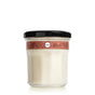 A glass jar with a black lid holds a creamy white substance, likely the Gingerbread Soy Glass Jar Candle by Mrs. Meyers. The jar features a brown label adorned with floral patterns and a small round logo at the center against a plain white background.