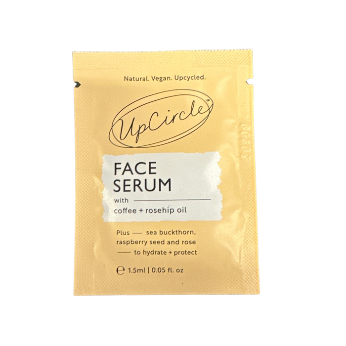 A yellow sachet of UpCircle Face Serum featuring coffee and rosehip oil. The packaging highlights that it is natural, vegan, upcycled, and contains sea buckthorn, raspberry seed, and rose to hydrate and protect.