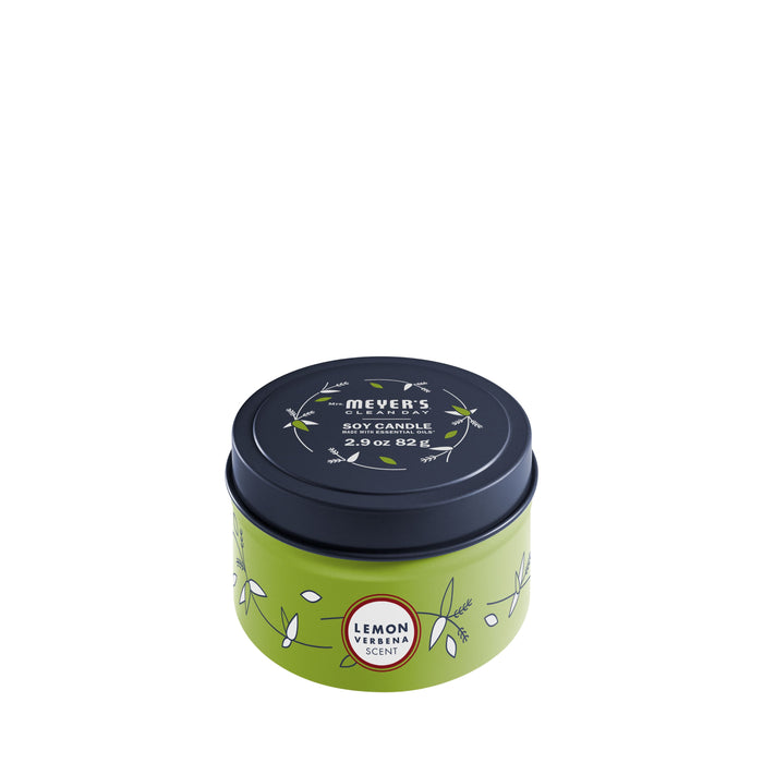 A small round tin of Mrs. Meyer’s Clean Day soy candle with a lemon verbena scent. The tin is light green with leaf designs and a black lid, featuring the product name and scent description.