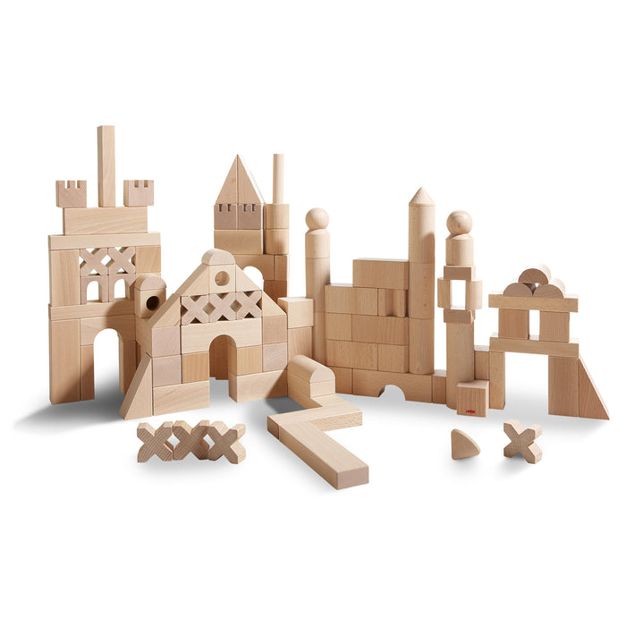 A variety of natural wooden building blocks arranged to form imaginative structures, including archways, towers, and geometric shapes, on a white background.
