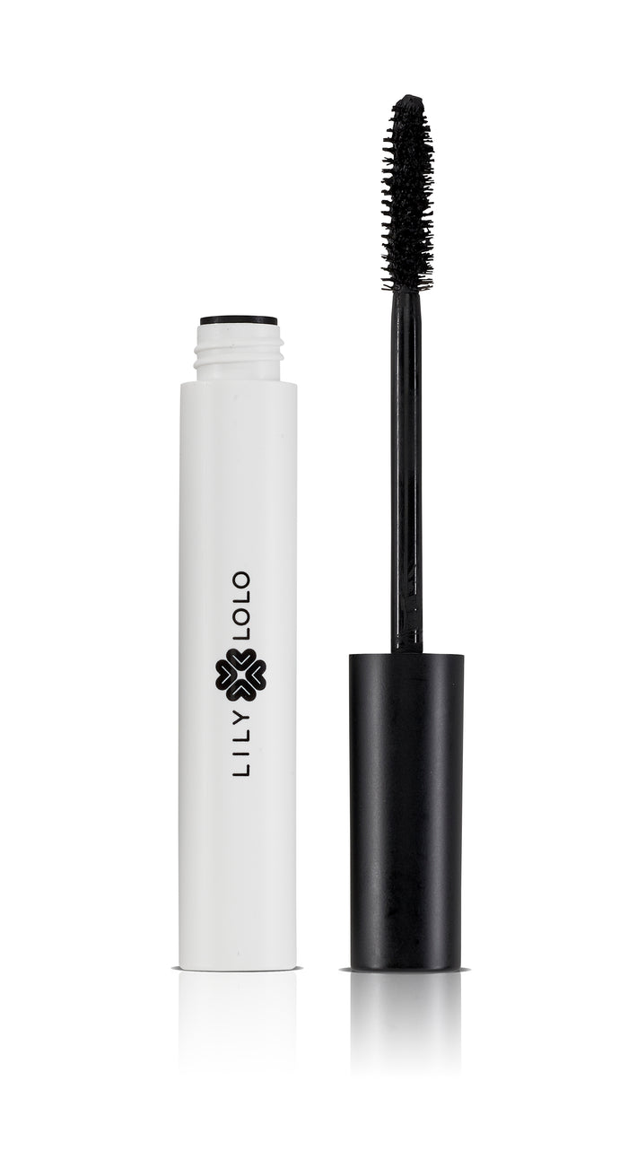 A white mascara tube with Lily Lolo branding stands next to its black wand applicator, which is upright and features a brush coated with black mascara. The background is plain white.
