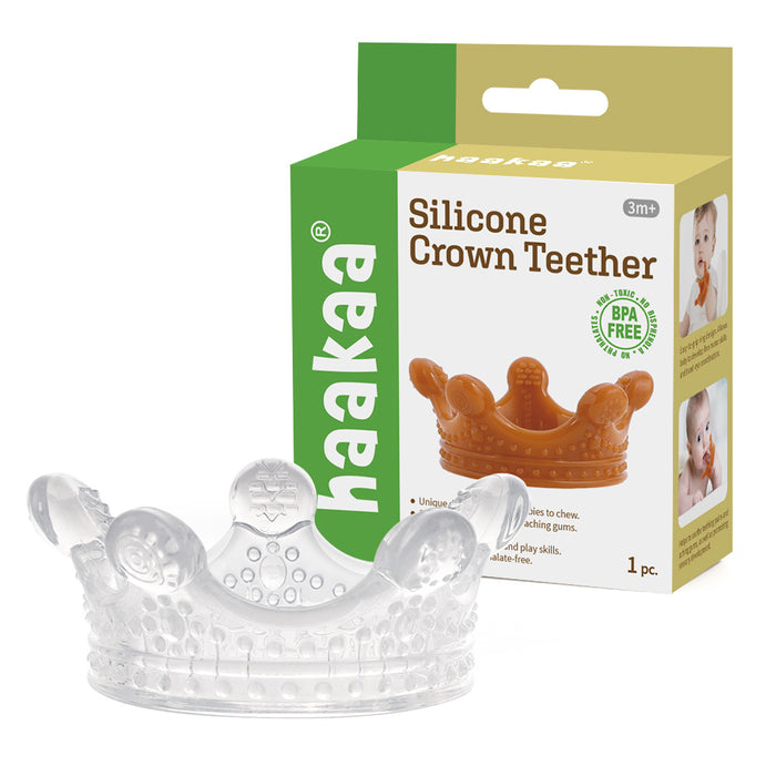 A clear silicone teether shaped like a crown sits in front of its packaging, which shows a photo of a baby and the text “Haakaa Silicone Crown Teether” for ages 3 months and up, highlighting that it is BPA free.