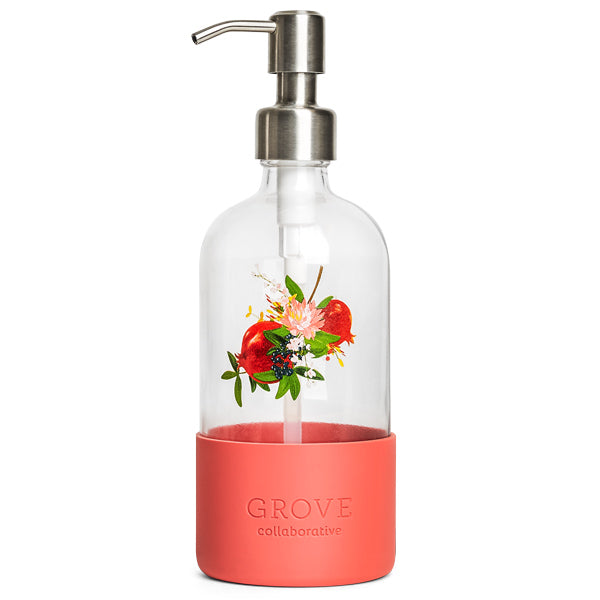 The Grove Co. refillable dish soap dispenser has a glass body, stainless steel pump, and coral silicone sleeve with floral and pomegranate designs. Grove Collaborative is embossed on the sleeve, making it ideal for those aiming to cut plastic waste in their sustainable home.