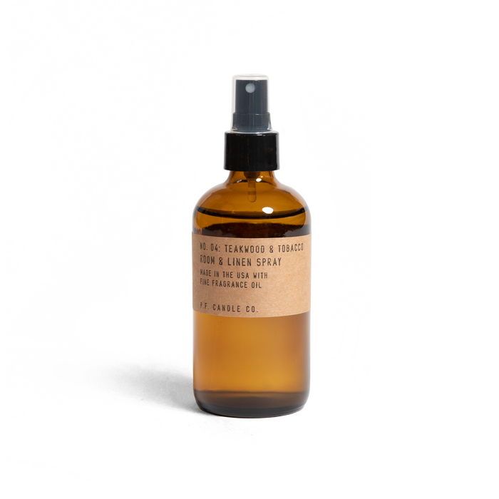 A brown glass spray bottle labeled No. 04: Teakwood & Tobacco Room & Linen Spray with a black spray top and a kraft paper label on a white background.