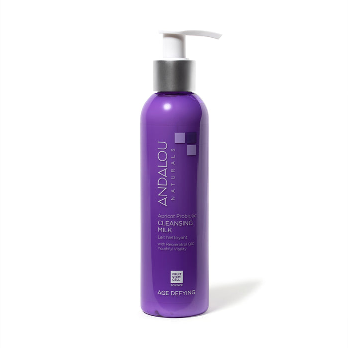 A purple pump bottle of Andalou Naturals Apricot Probiotic Cleansing Milk labeled Age Defying. The bottle has silver and white accents and text describing its contents and benefits.
