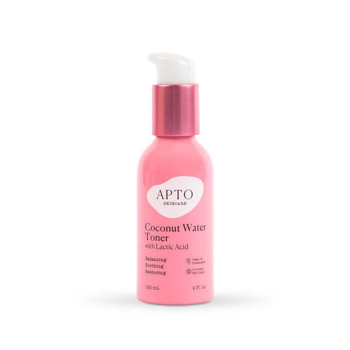 A pink bottle of APTO Skincare Coconut Water Toner with Lactic Acid, featuring a white pump and metallic pink collar. The label highlights benefits: balancing, soothing, and restoring. Bottle size is 120 mL (4 fl oz).