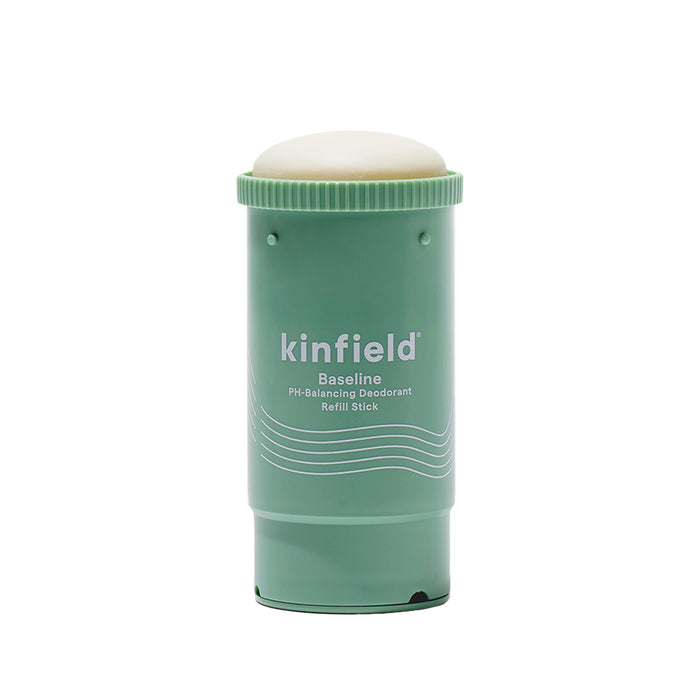 A green cylindrical Kinfield Baseline deodorant stick with a rounded white top, labeled PH-Balancing Deodorant Refill Stick. The container features white text and wavy lines.