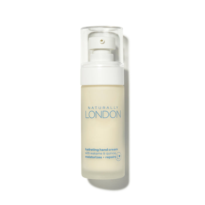 A clear pump bottle of Naturally London Hydrating Hand Cream with wakame and quinoa, labeled to moisturize and repair, set against a white background.