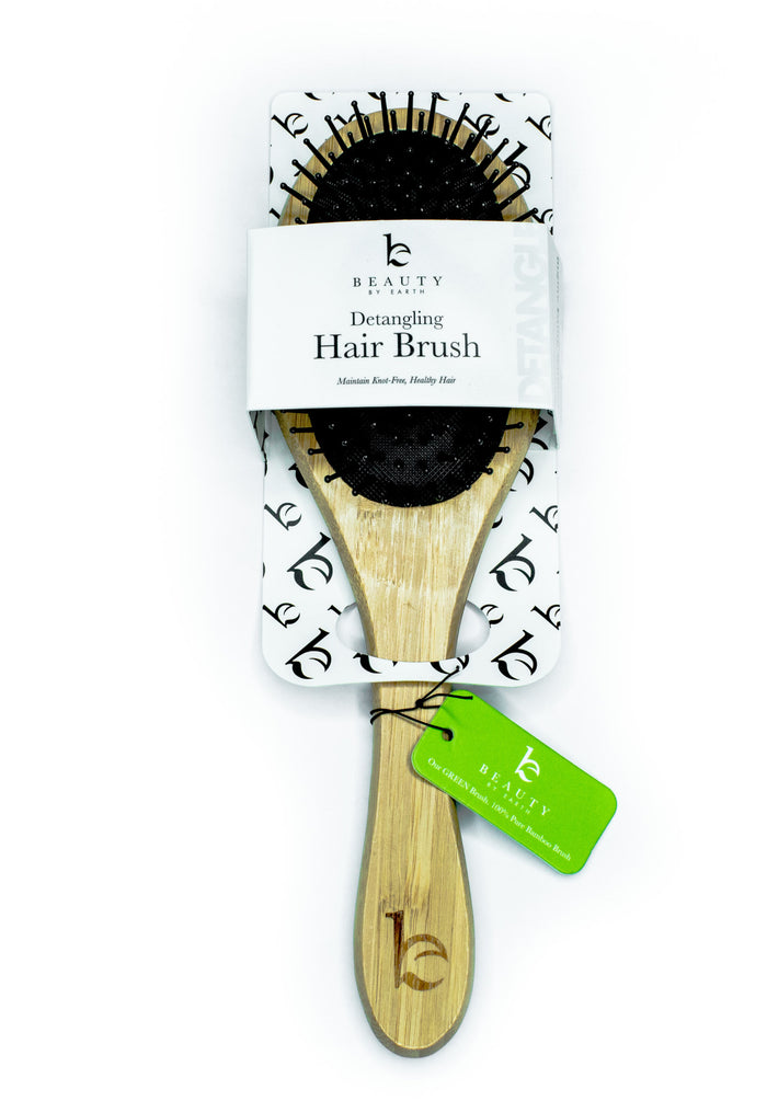 A wooden-handled detangling hair brush in packaging labeled Beauty Detangling Hair Brush with black bristles and a green tag attached to the handle.