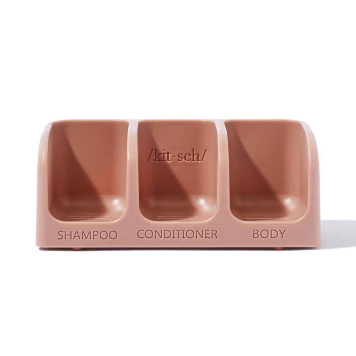 A pink three-slot shower caddy labeled SHAMPOO, CONDITIONER, and BODY, with /kit-sch/ written above the middle compartment.