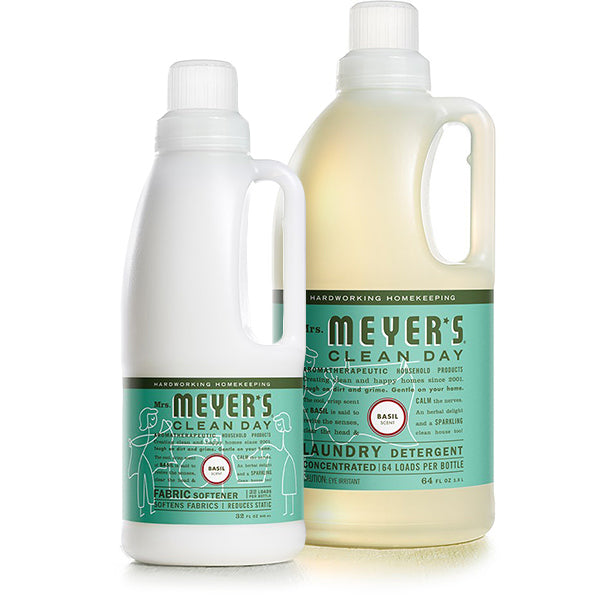 The Mrs. Meyers Laundry Detergent & Fabric Softener Set includes two green-labeled bottles featuring a basil scent: a larger detergent and smaller fabric softener. Both have ergonomic handles and a minimalist design, ideal for an elegant home cleaning ritual.
