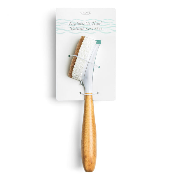 A dish scrubber with a wooden handle and a replaceable head is attached to a white card labeled Grove Replaceable Head Potbrush Scrubber. The scrubber head has a white and brown textured surface.