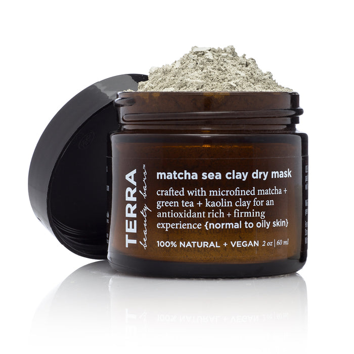 A brown jar labeled TERRA Matcha Sea Clay Dry Mask with its black lid open, showing light green powder inside. The label notes its for normal to oily skin and made with natural, vegan ingredients.