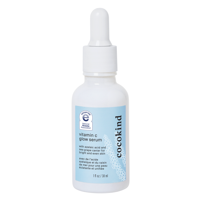 A white dropper bottle of Cocokind Vitamin C Glow Serum with a light blue label, featuring product details and a seal indicating acceptance by the National Eczema Association.