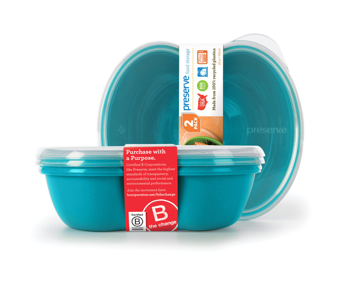 Two turquoise plastic food storage containers with lids, branded Preserve. Packaging highlights that they are made from recycled materials, BPA-free, and dishwasher safe. A red label promotes sustainability and certification.