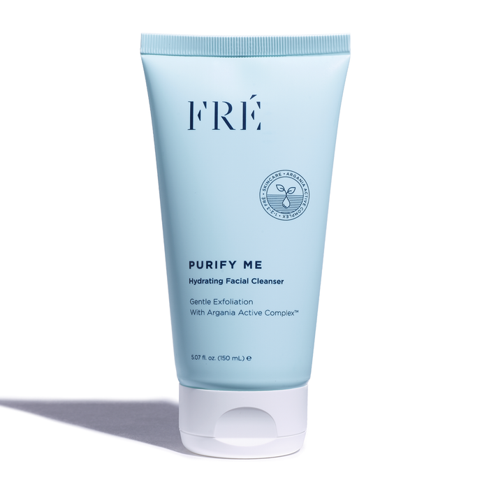 A blue tube of FRÉ Purify Me Hydrating Facial Cleanser with a white cap, standing upright on a white background. The label highlights gentle exfoliation and Argania Active Complex.