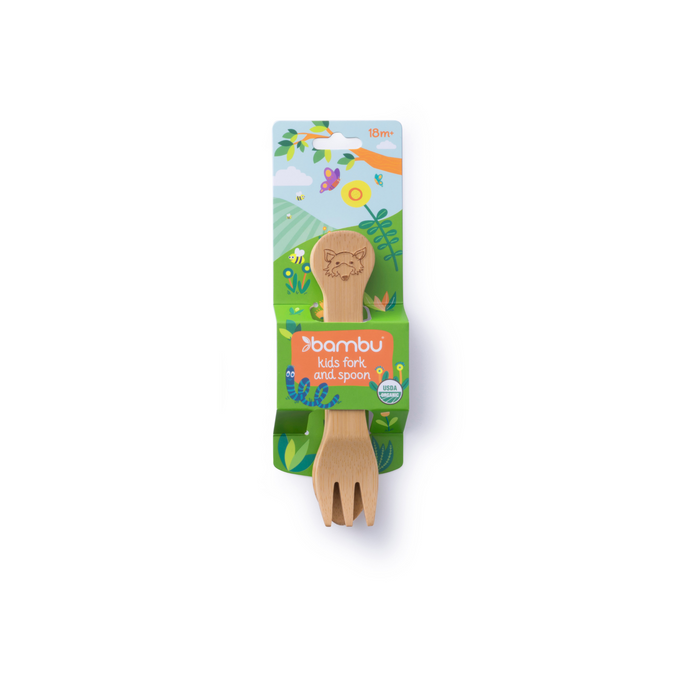 A bamboo kids fork and spoon set from the brand Bambu, packaged with colorful, nature-themed backing featuring hills, trees, and a sun. The utensils have an animal face engraved on the handles.