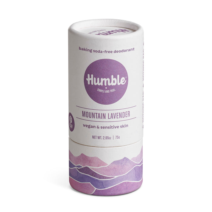 A cylindrical stick of Humble deodorant in Mountain Lavender scent. The packaging is white with purple text and mountain illustrations, labeled vegan, sensitive skin, and baking soda-free.