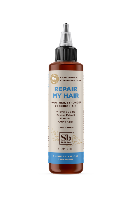 A brown bottle of Soapbox Repair My Hair treatment with a pointed applicator. The label highlights vegan ingredients, vitamins, flaxseed, amino acids, and banana extract. The bottle contains 5 fl oz (147 ml).