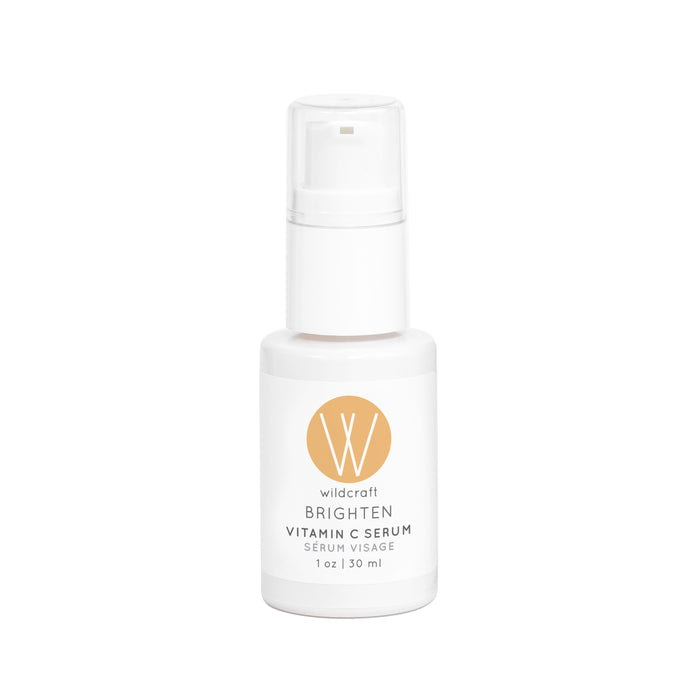 A white bottle of Wildcraft Brighten Vitamin C Serum with a pump dispenser and a yellow circular logo on the front. The label indicates it contains 30 ml (1 oz) of serum for the face.