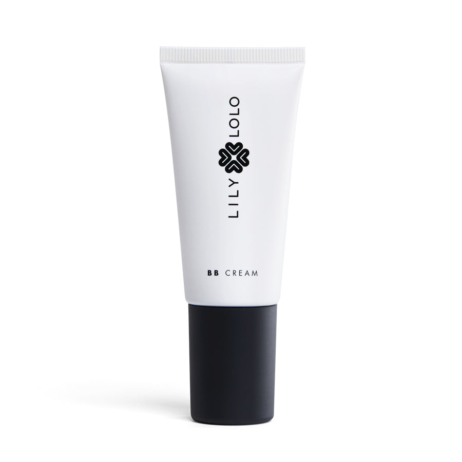 A white tube of Lily Lolos Natural BB Cream with a black cap features a minimalist design with the brands name in vertical black letters. This silicone-free Beauty Balm, enhanced with mineral pigments, ensures a flawless finish.
