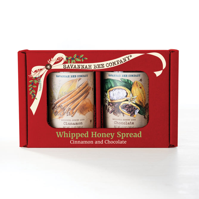 The Savannah Bee Company Cinnamon & Chocolate Whipped Duo gift box includes two jars—Cinnamon Honey and Chocolate Spread—with illustrated labels showcasing the honey and its tasty ingredients.