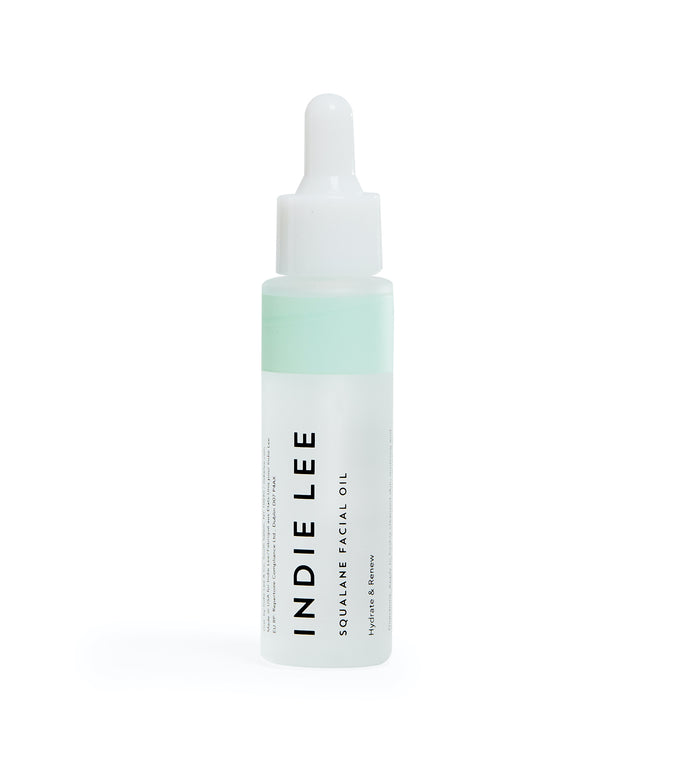 A clear bottle of Indie Lee Squalane Facial Oil with a dropper cap, featuring minimalist white and mint green labeling and black text.