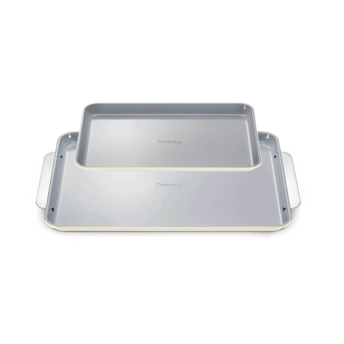 Two light gray rectangular baking sheets with raised edges, one larger pan with handles underneath a smaller pan without handles, both placed on a white background.