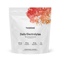 A white Thorne Daily Electrolytes pouch (Blood Orange Flavor) features red and orange watercolor at the top. The front highlights sodium, potassium, magnesium, 0g sugar, and notes support for cellular hydration and athletic performance.