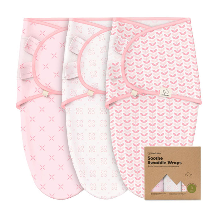Three pink and white baby swaddle wraps with different patterns (crosses, circles, chevrons) are displayed next to a brown box labeled Soothe Swaddle Wraps.