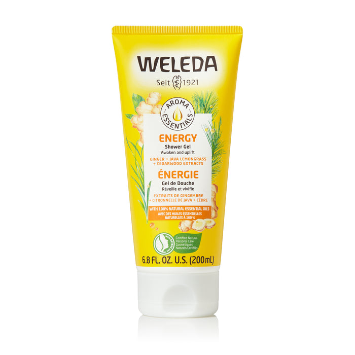 A yellow tube of Weleda Energy Shower Gel with ginger, java lemon, and cedarwood extracts. The 200ml tube features green and orange accents, aromatics imagery, and bilingual labeling in English and French.