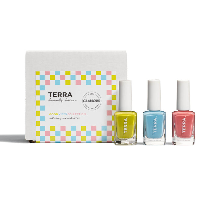 Three bottles of Terra nail polish—yellow, blue, and pink—stand in front of a white, pastel-checkered box labeled “Terra Beauty Bars Good Vibes Collection.” The packaging features a Glamour award badge.
