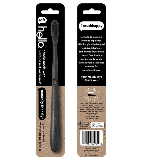 A black toothbrush with plant-based handle and charcoal bristles is displayed in eco-friendly packaging. Text highlights its softness, bamboo and corn fiber materials, and encourages “#brushhappy.”.