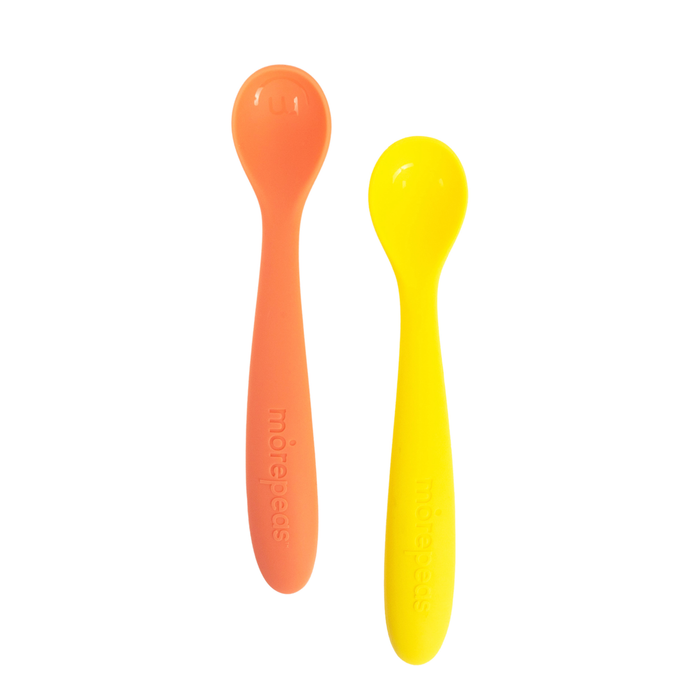 Two silicone baby spoons, one orange and one yellow, are placed side by side on a white background. Both spoons have smooth, rounded heads and handles with “motrpecks” embossed on them.