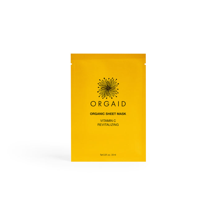 A bright yellow packet of Orgaid Organic Sheet Mask, labeled Vitamin C Revitalizing, stands upright against a plain white background. The packaging features a black botanical illustration and text.