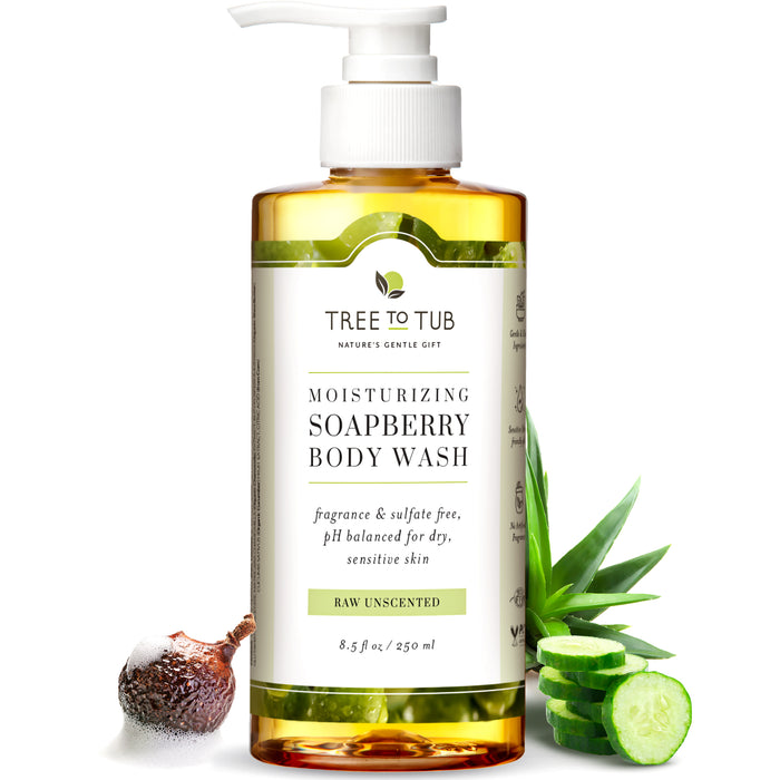 A bottle of Tree To Tub Moisturizing Soapberry Body Wash sits upright, labeled as raw unscented and pH balanced for dry, sensitive skin. Around it are a soapberry, aloe vera, and cucumber slices.